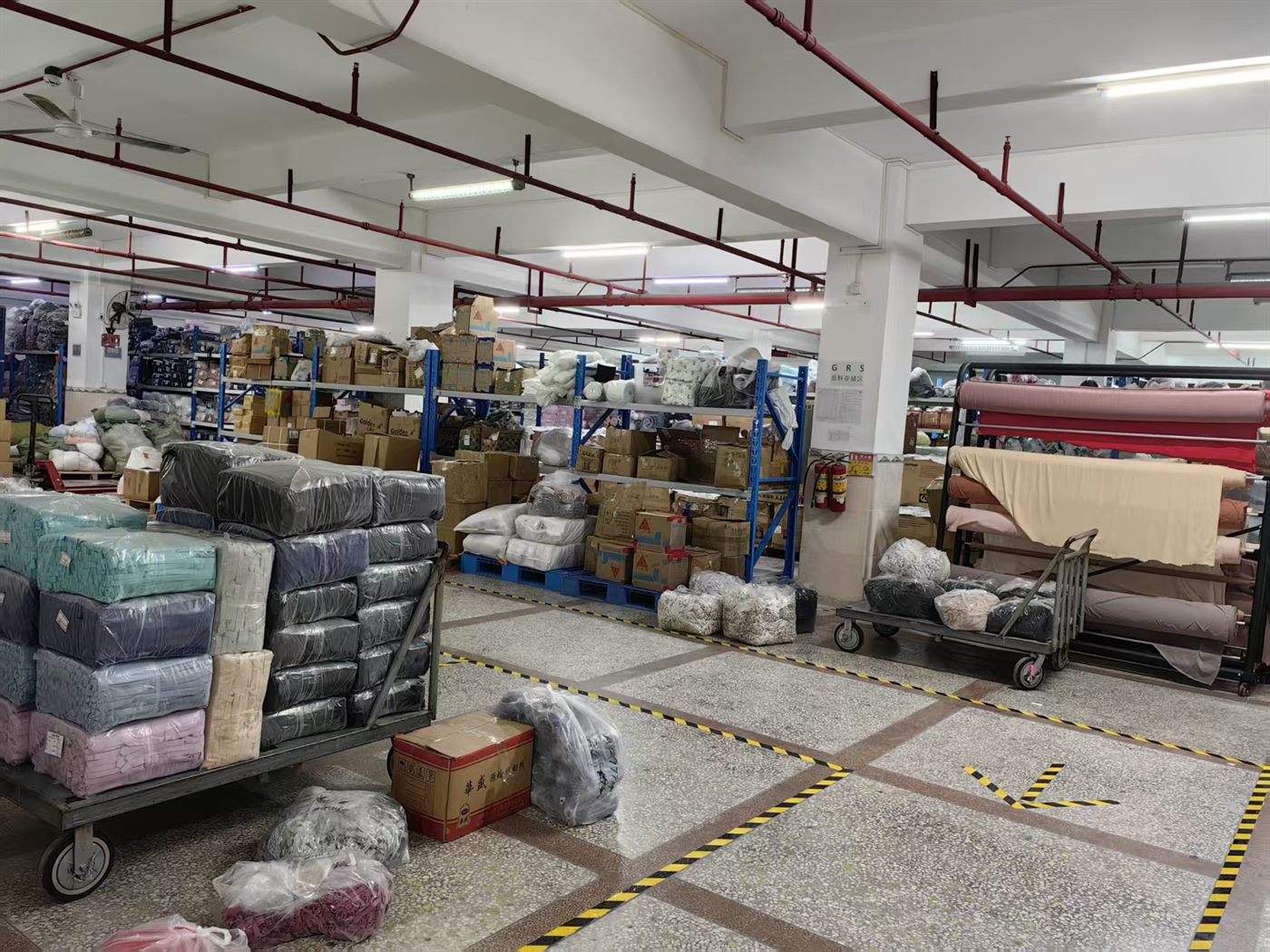 LJVOGUES 面料仓库实拍:货架与周转车码放待产面料,泳衣及经期裤面料分区管理